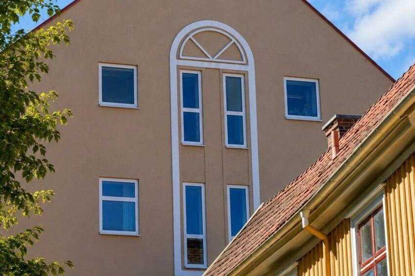 A building with a beige facade, a central arched window, and a red-tiled roof. 5