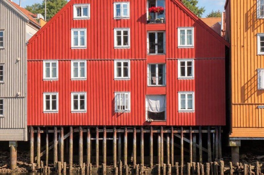 A red building with white windows, wooden stilts, and a balcony with flowers. 2