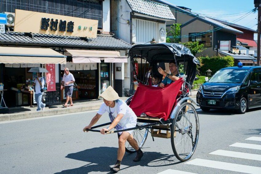 A street scene with a rickshaw, a person pushing it, and a storefront with signage. 4