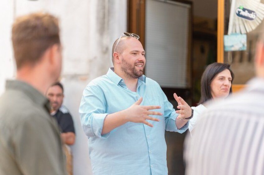 A person in a light blue shirt gesturing while speaking to others. 3