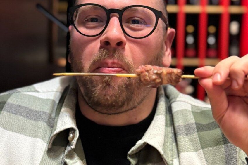 A person holding a skewer with food. 4