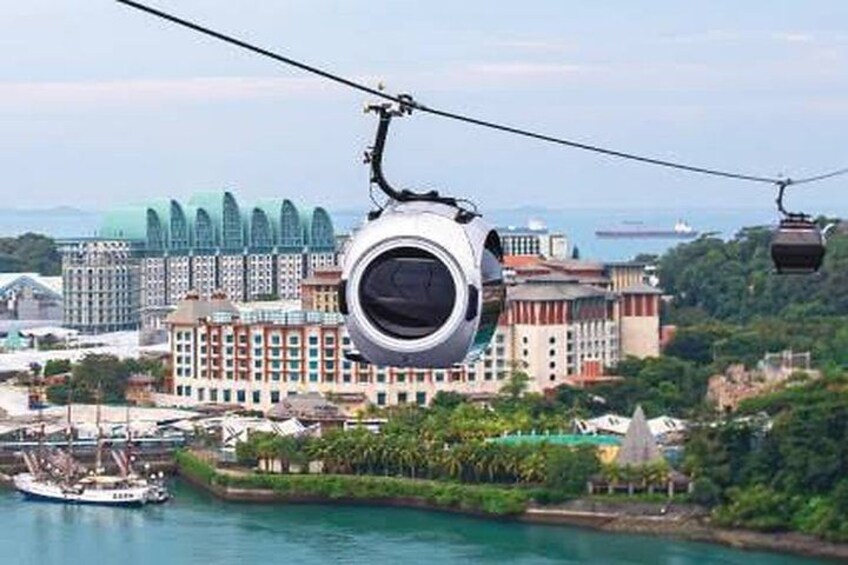 A cable car system with a gondola suspended over a body of water, buildings in the background, and a distant view of a cityscape. 5
