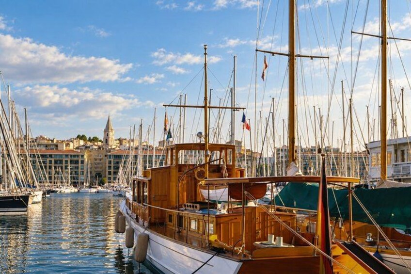 A harbor with multiple sailboats docked, a prominent wooden boat in the foreground, and a historic building in the background. 3
