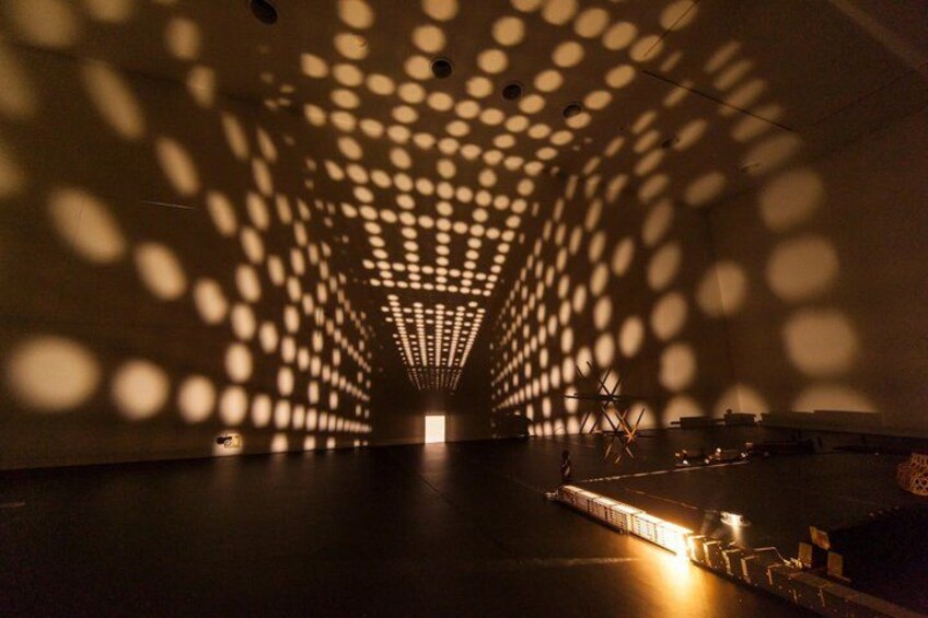 A dimly lit interior space with a patterned ceiling and a central light source. 2
