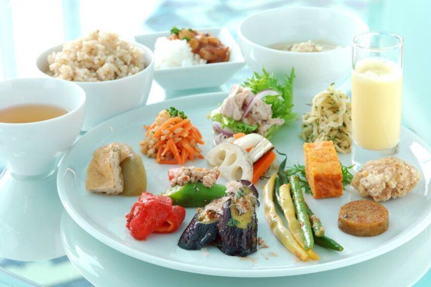 A variety of dishes including rice, vegetables, and meat on a plate, accompanied by bowls of soup and a glass of milk. 5