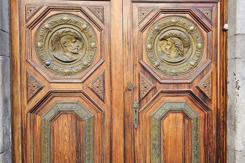 A wooden door with intricate carvings and a brass emblem. 4