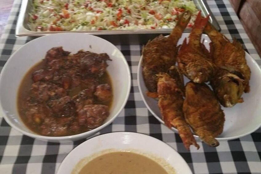 A table with a dish of fried fish, a bowl of stew, and a plate of salad. 4