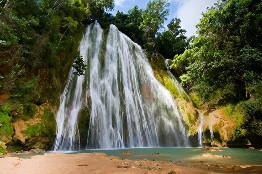 A waterfall cascading into a clear pool surrounded by lush greenery. 2
