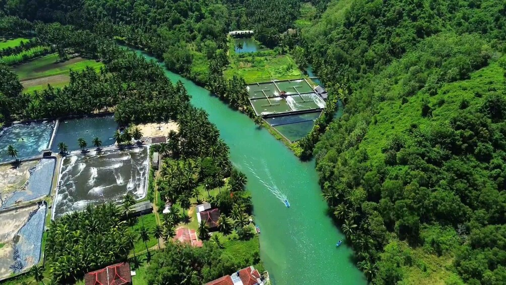 A river winding through a lush green landscape with a boat in motion. 1