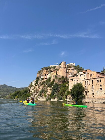 A river with kayaks, a castle on a hill, and a clear blue sky. 2