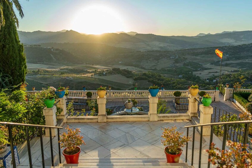 Eine Terrasse mit Blumentöpfen und Blick auf ein Tal mit Bergen im Hintergrund. 3
