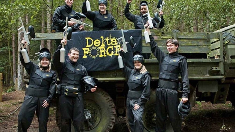 A group of individuals in tactical gear standing in front of a military vehicle with a banner. 5