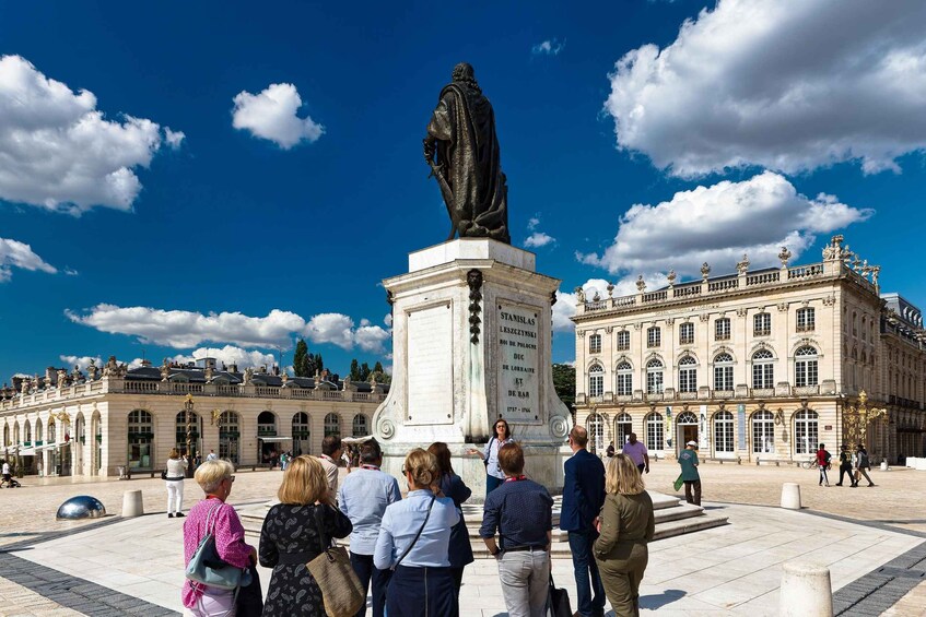 A statue in front of a historic building with people gathered around it. 2