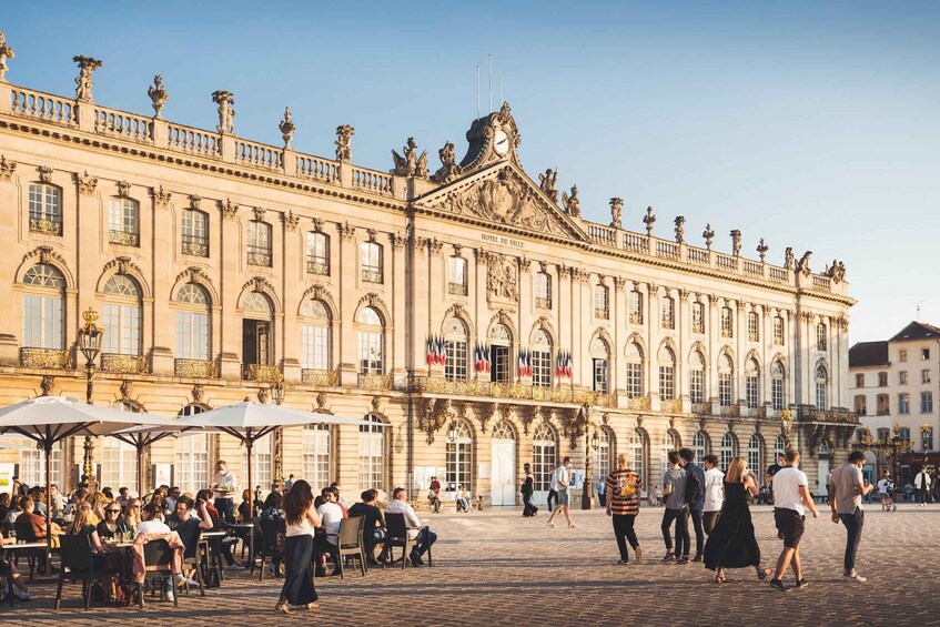 A historic building with ornate architecture, flags, and outdoor seating for people. 4