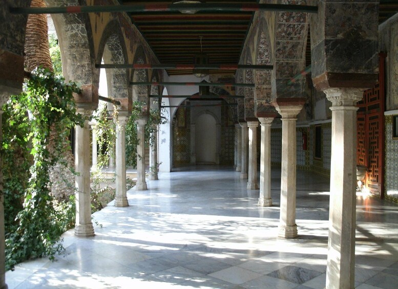 An indoor courtyard with columns, arches, and patterned walls. 2