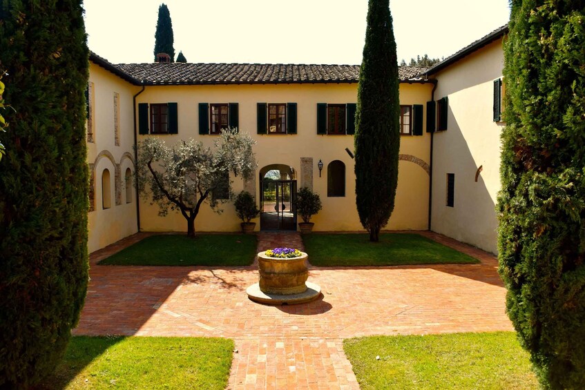 A courtyard with a central flower bed, surrounded by neatly trimmed hedges and a tiled floor. 3