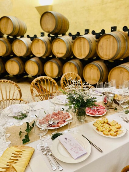 A table set for a wine tasting event with wine glasses, plates of food, and a menu. 5