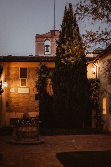 A courtyard with a bell tower, a tree, and a building with a tiled roof. 4