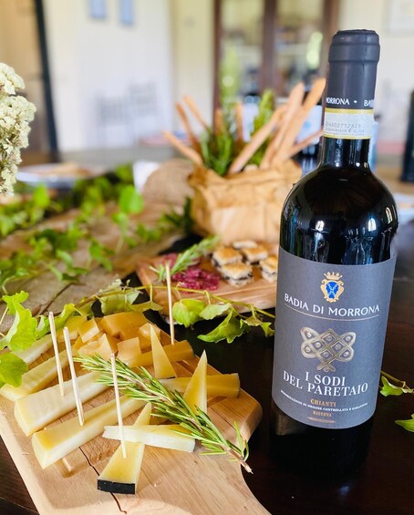 A bottle of Badia di Morrona I Sodi del Paretaio wine with a wooden cheese board in the foreground. 1