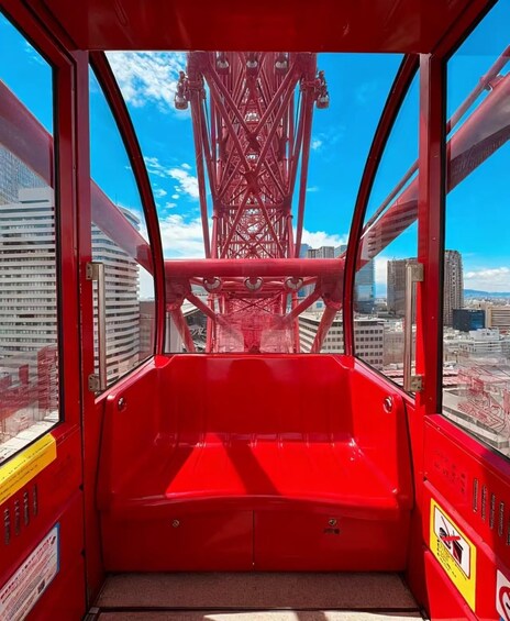 Une télécabine rouge offrant une vue sur une haute tour rouge et sur les bâtiments de la ville. 2
