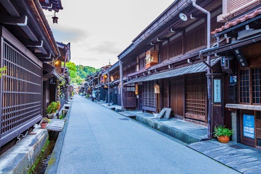 A traditional Japanese street with wooden buildings, a clear sky, and a narrow road. 1