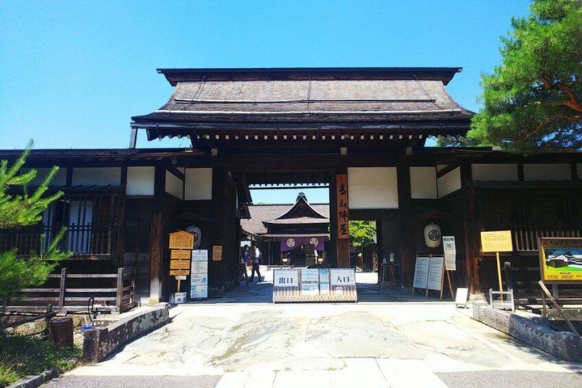 A traditional Japanese gate with a tiled roof and wooden structure. 2