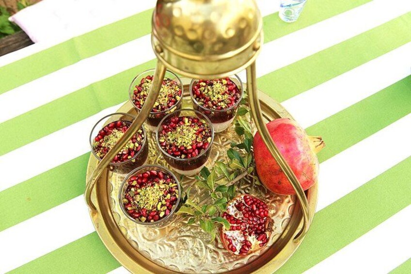 A tray with glasses of pomegranate juice garnished with nuts, a pomegranate, and a decorative metal stand. 2