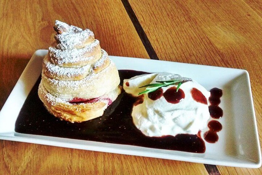 A dessert on a white plate with powdered sugar and a berry sauce. 3