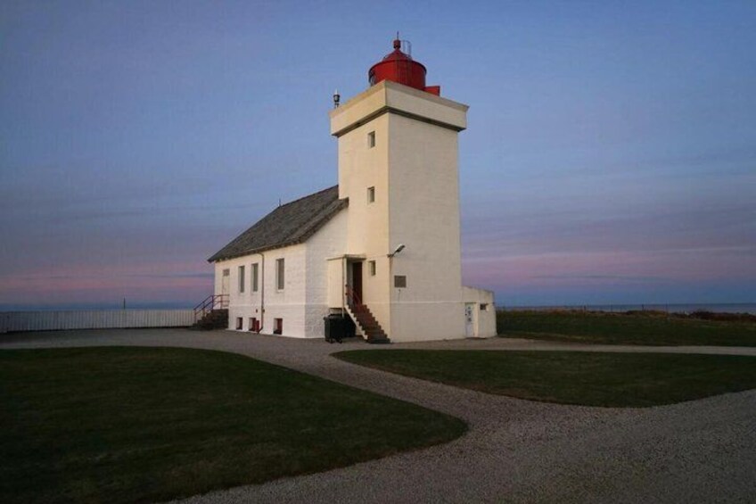 A lighthouse with a red top, a white base, and a gravel path leading to it. 5