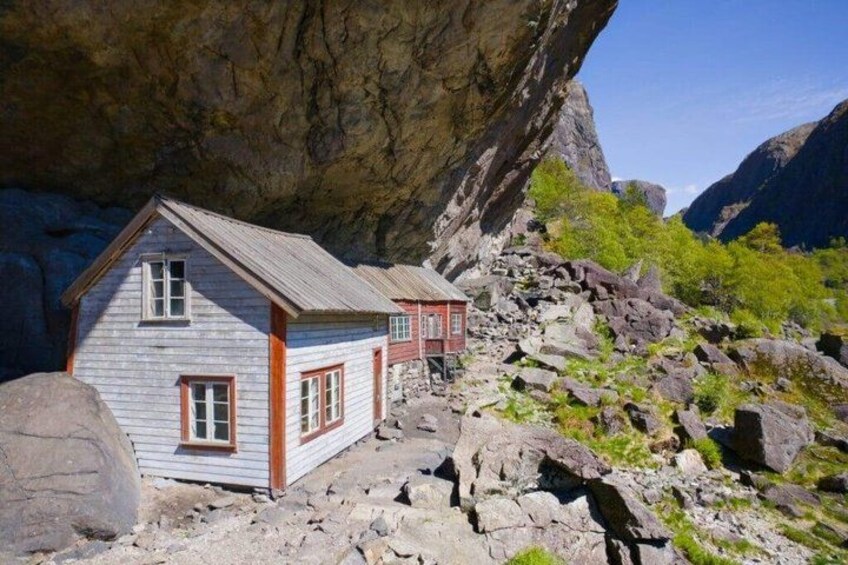 A small wooden cabin with a red roof nestled in a rocky landscape. 1