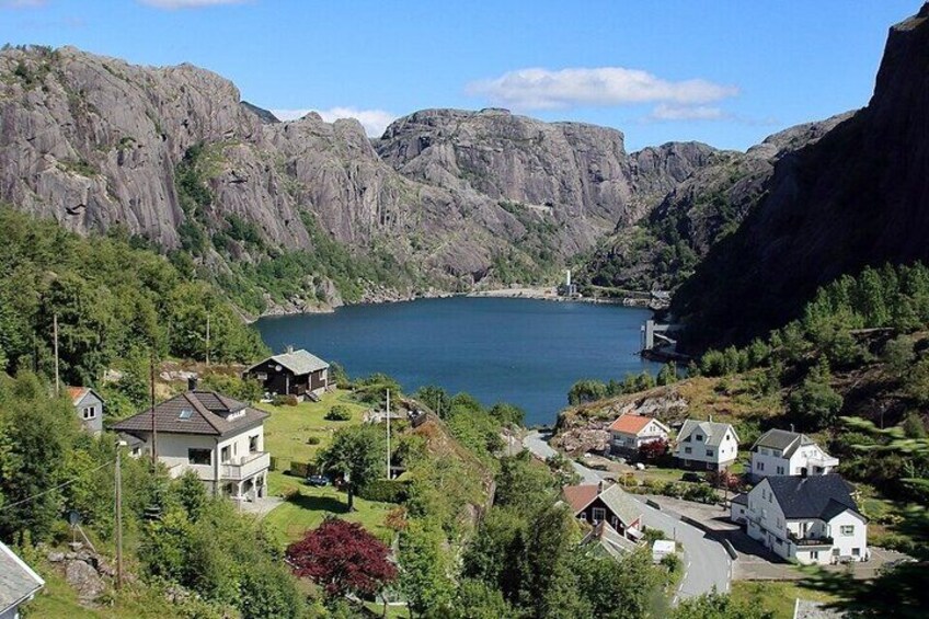 A lake surrounded by rocky cliffs, houses, and greenery. 4