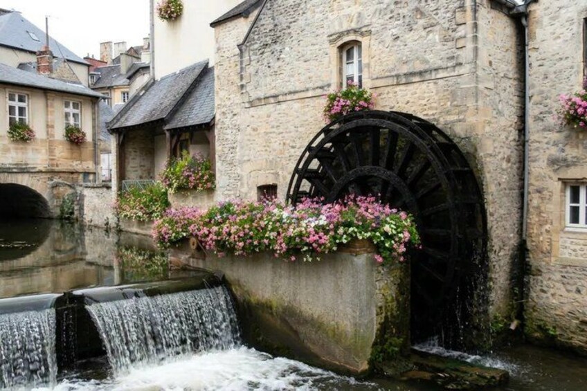 A historic stone building with a large water wheel and a flowing stream. 5