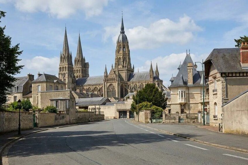 A cathedral with pointed spires, a curved road, and surrounding buildings. 1