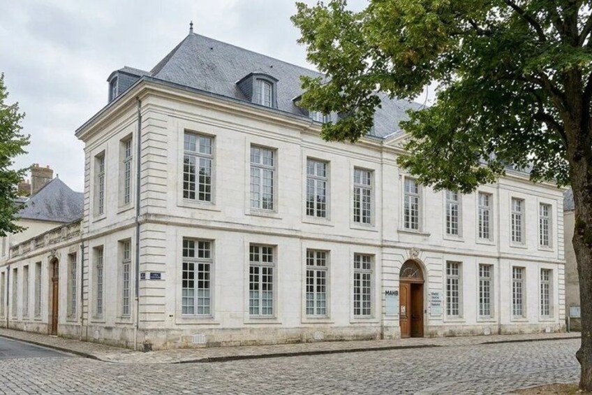 A historic building with a symmetrical facade, large windows, and a central entrance. 3