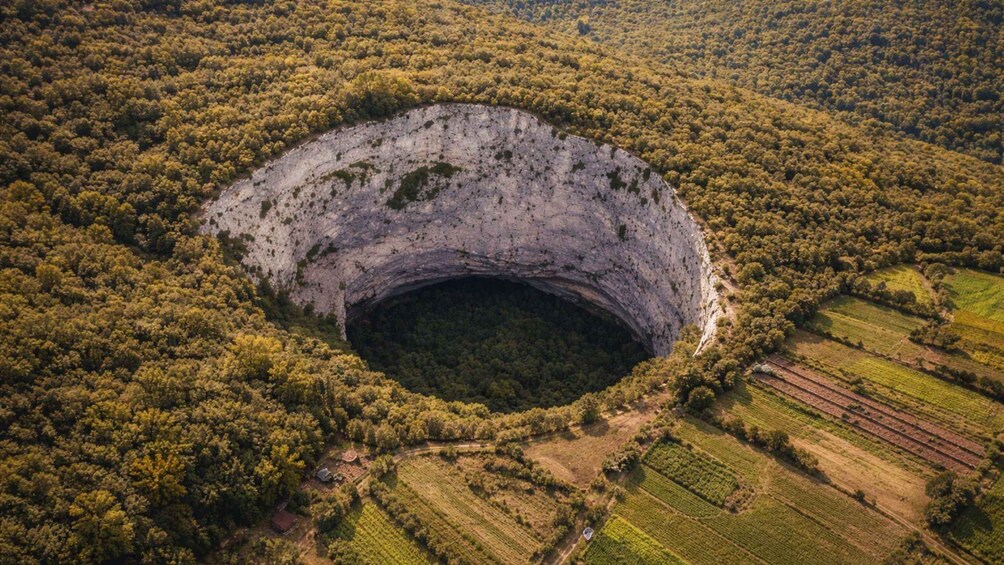 A large crater surrounded by dense forest and agricultural fields. 1