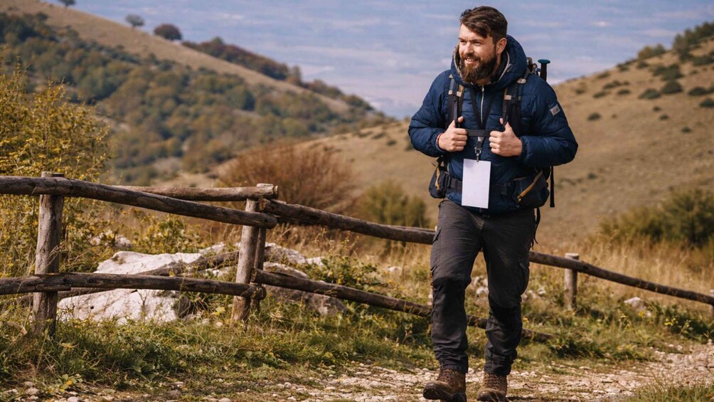 A person hiking on a trail with a backpack, surrounded by a hilly landscape and a wooden fence. 3