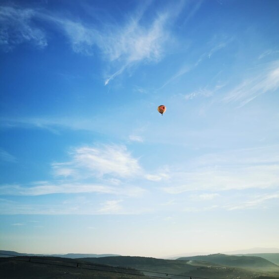 Un ballon à air chaud dans un ciel bleu clair, parsemé de quelques nuages légers. 5