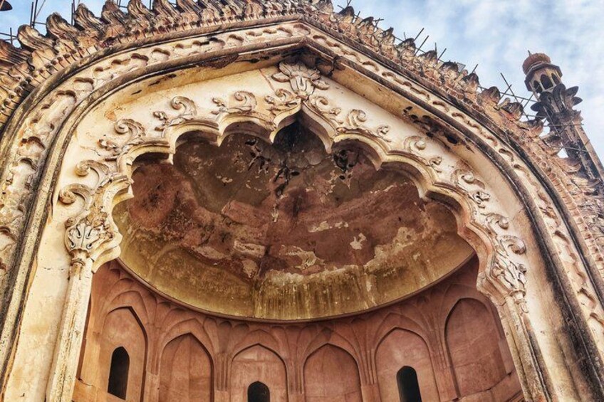 Una estructura arquitectónica ornamentada y desgastada, con tallas intrincadas y un gran arco central dañado. 3