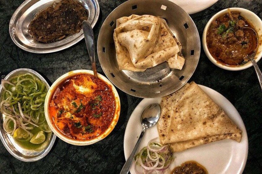 Variedad de platos indios, como pan naan, curry y cebollas en rodajas como guarnición. 2