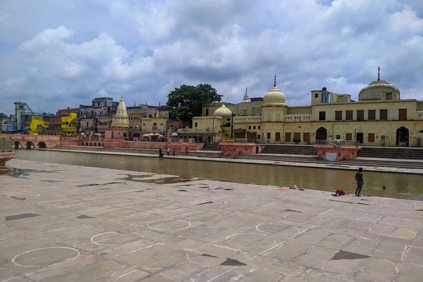A riverside view with a large building with domes, a bridge, and a person standing by the water. 3