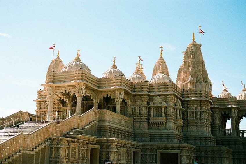 A large, intricately carved temple with multiple domes and spires, featuring detailed stonework and a prominent staircase leading to the entrance. 2