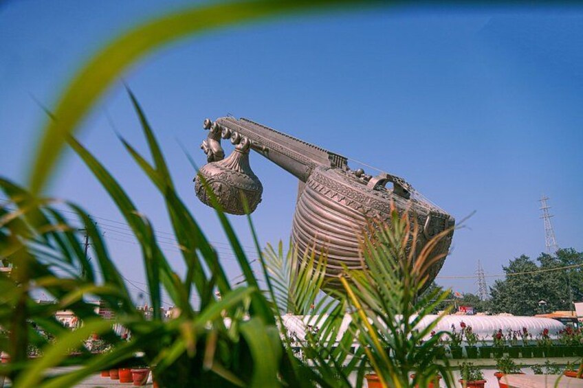 A large metallic sculpture with a curved structure and a spherical element, set against a clear blue sky. 4
