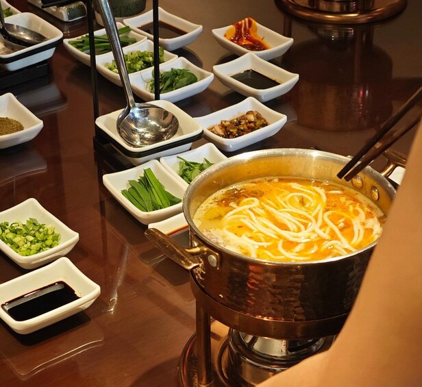 A hot pot with various ingredients and sauces on a table. 1