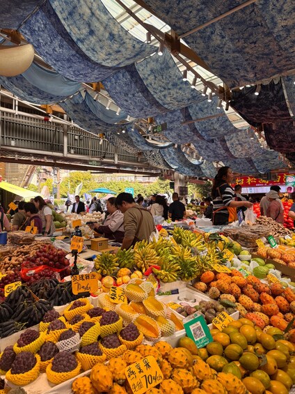 Un marché animé où l’on peut trouver une grande variété de fruits et de légumes, notamment des bananes, des oranges et des melons. 3