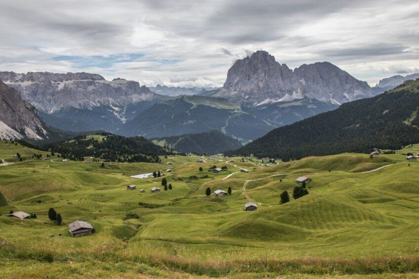 A mountainous landscape with green fields, scattered houses, and a prominent rocky peak in the background. 2