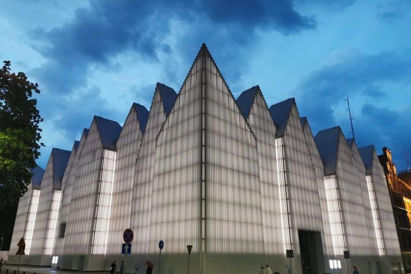 A large, modern building with a distinctive triangular roof structure. 4