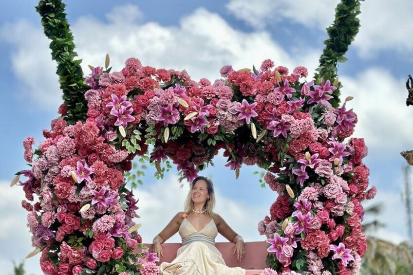 A person seated under a floral arch with pink and purple flowers. 3