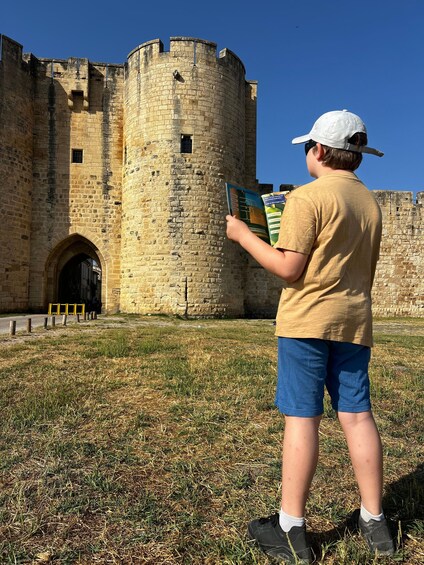 Une personne est assise devant un château de pierre historique et lit un livre. 2
