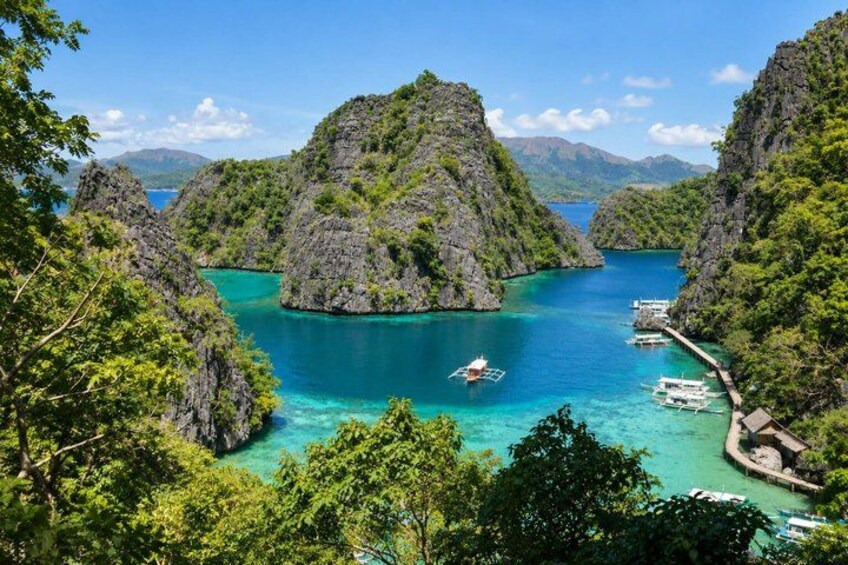 A coastal landscape with rocky islands, clear turquoise waters, and boats. 3