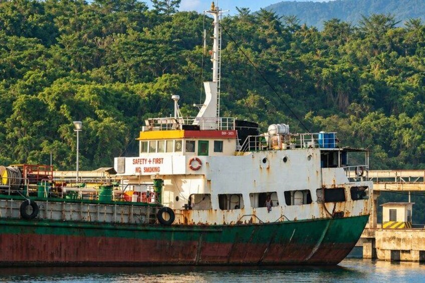 A large, rusty ship docked at a pier with a sign that reads 'SAFETY + FIRST NO SMOKING.' 5